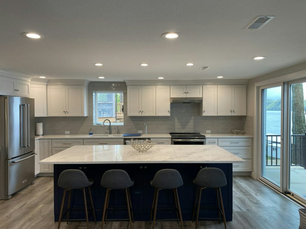 A modern kitchen with a grey and navy blue island at the lake