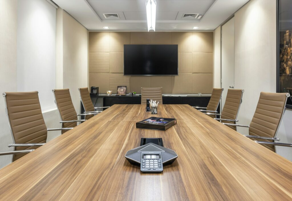 Shot of an office interior with long table, TV, comfortable chairs, projector, lighting, glass door