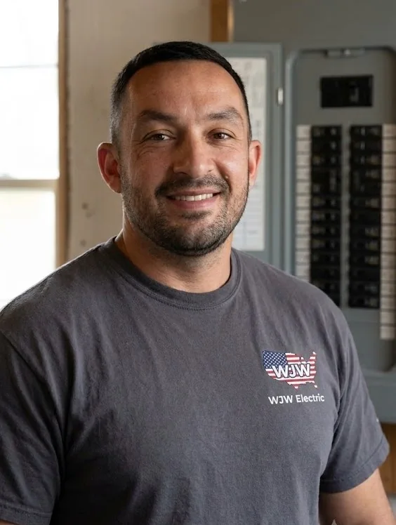 Billy Webber, master electrician and owner of WJW Electric, standing beside an electrical panel in Pepperell MA